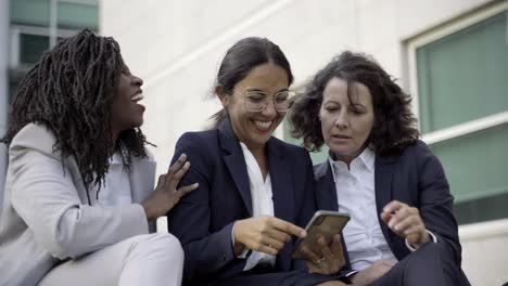 Smiling-women-looking-at-smartphone-during-break